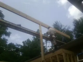 Carpenter setting a ridge beam over a new addition frame — Ice Dam Removal by Roofing Brothers in Newtonsville