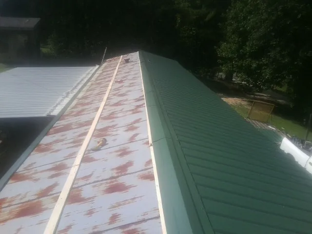 Old rusted panels beside newly installed green metal roofing — Wind Damage Roof Repair by Roofing Brothers in Newtonsville