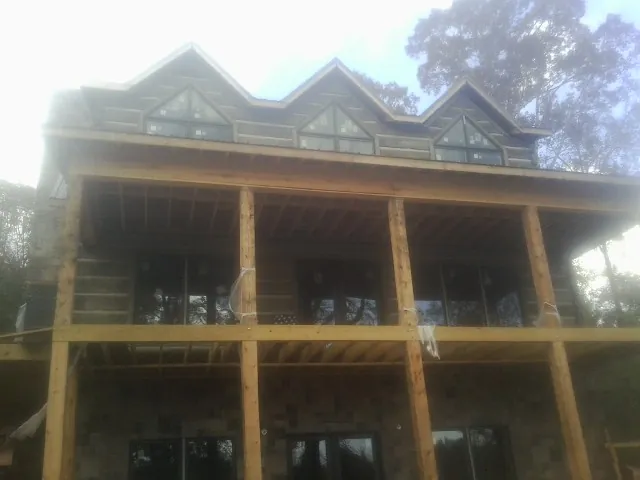 Dormers and porch framing on a large log home under construction — Roof Coating work by our crew in Newtonsville