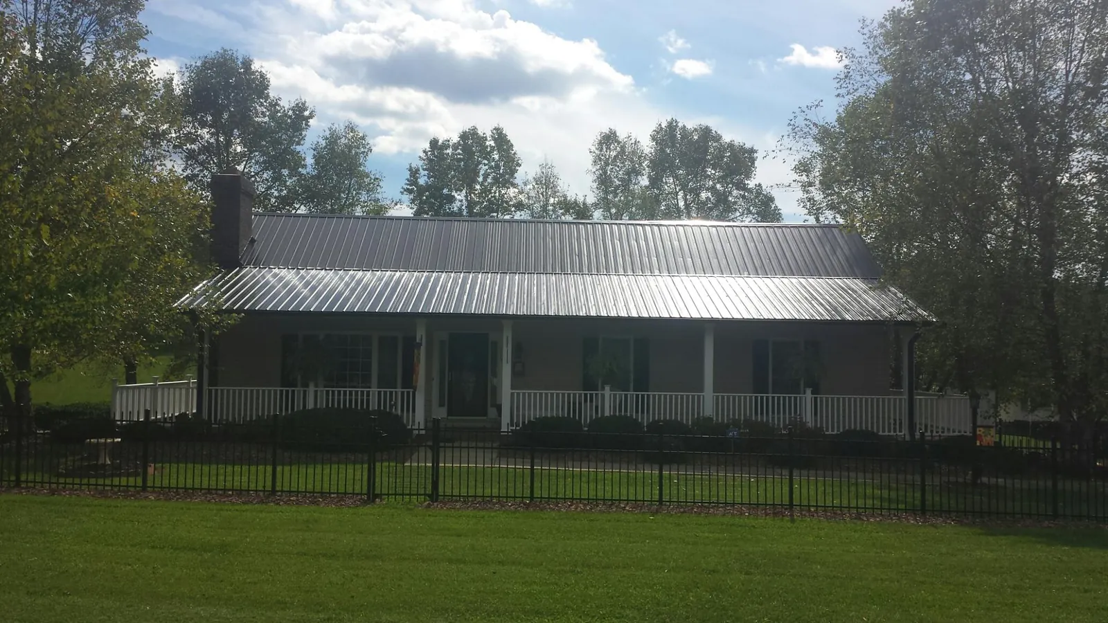 Gray metal roof on a brick ranch with a full width front porch — Gutter Guard Installation work by our crew in Newtonsville