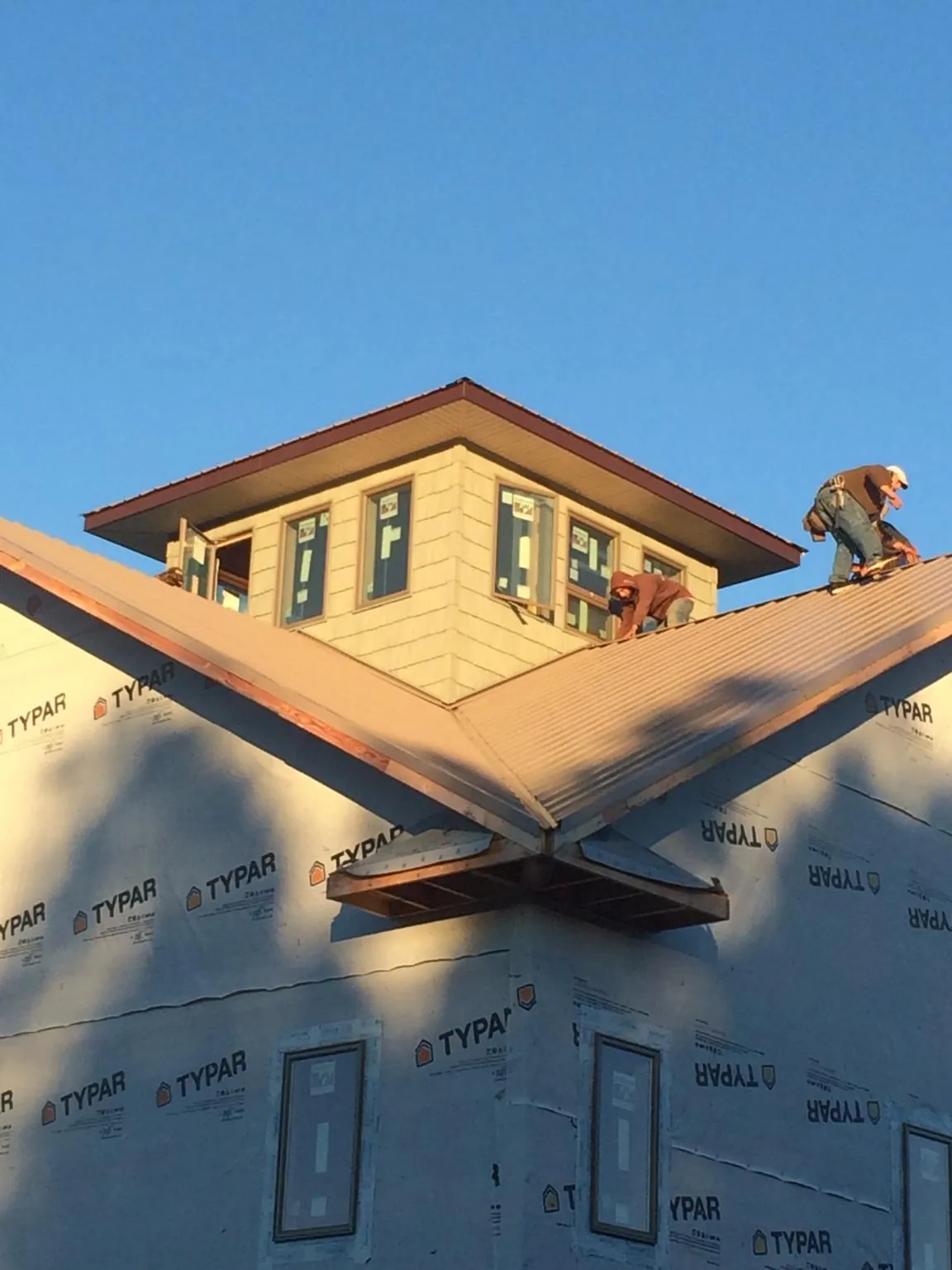 Roofers working around a rooftop cupola on a new metal roof at sunset — Roof Waterproofing in Newtonsville by Roofing Brothers